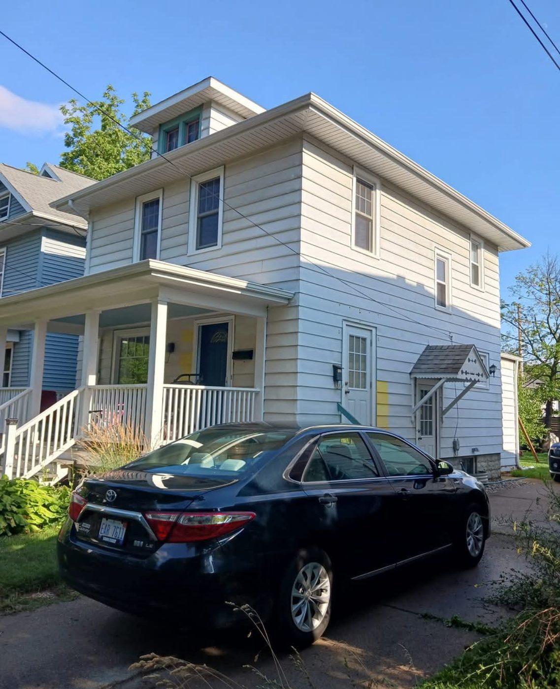 Two-storey house with tired white siding before an exterior repaint