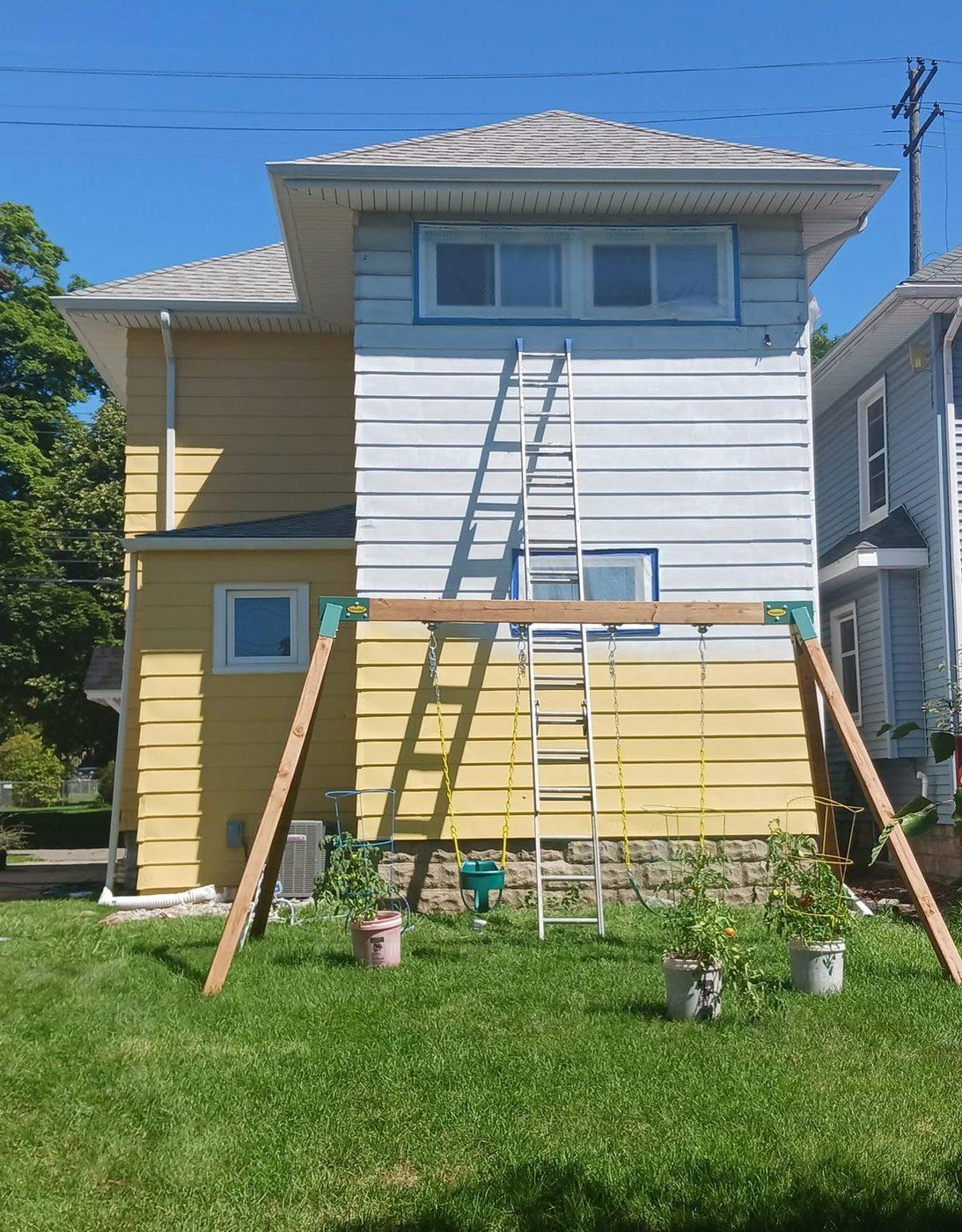 The same house part way through the repaint, lower storey painted and a ladder against the wall