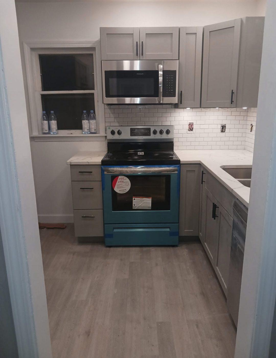 Finished kitchen with grey cabinets, a tiled splashback and a new range